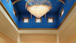 A grand interior with a central staircase, ornate railings, and a chandelier. - WelcomHeritage Sheikhpura Kothi (Hansi)