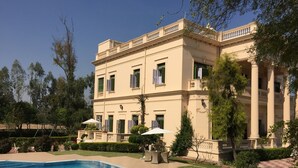 A large, two-story building with a swimming pool, outdoor seating, and a well-maintained garden. - WelcomHeritage Sheikhpura Kothi (Hansi)