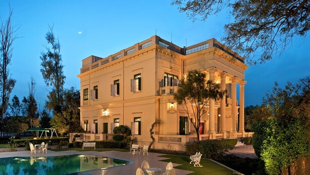 A large, classical building with a swimming pool and outdoor seating. - WelcomHeritage Sheikhpura Kothi (Hansi)