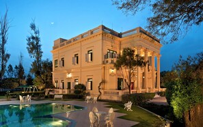 A large, classical building with a swimming pool and outdoor seating. - WelcomHeritage Sheikhpura Kothi (Hansi)