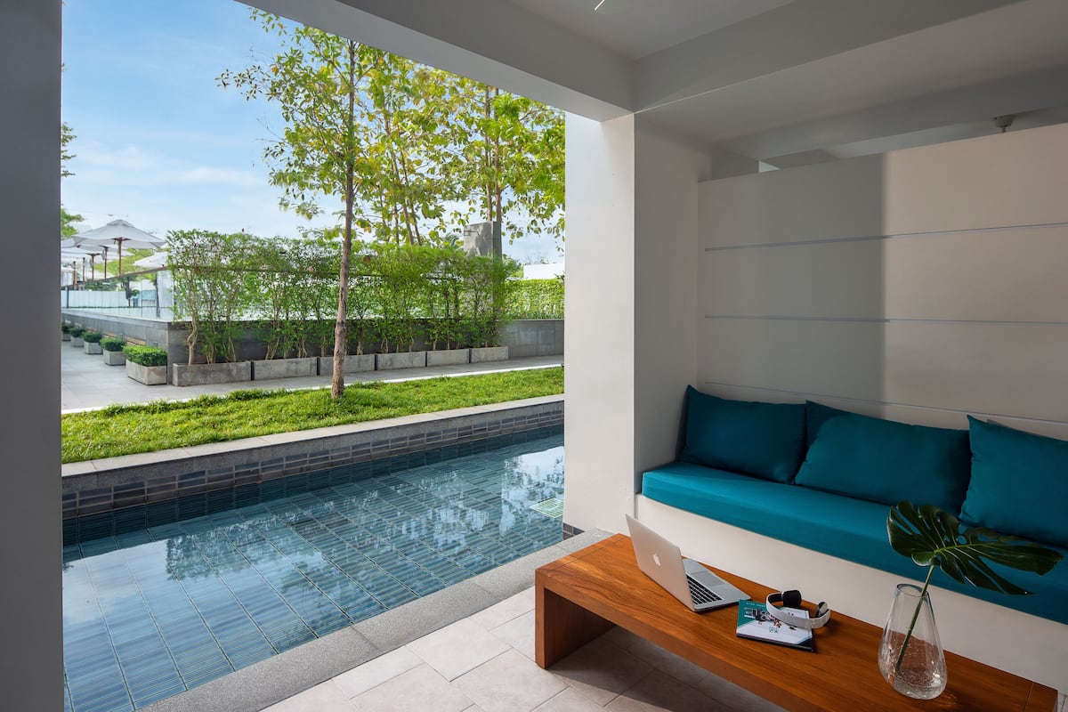 A modern living room with a view of a swimming pool and a garden.