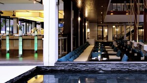 Un moderno vestíbulo de hotel con mostrador de recepción, zona de estar y una escalera que conduce a plantas superiores.