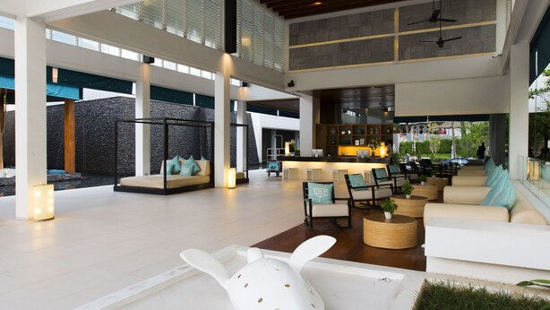 Un espacio interior amplio con techo alto, zona de estar con sofás y sillones, y una cocina central.