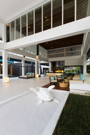 A spacious indoor area with a high ceiling, a seating area with sofas and chairs, and a central kitchen area. - Nap Patong (Patong)