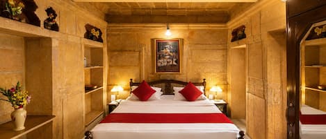 A room with a bed, two bedside lamps, a ceiling fan, and a painting on the wall.