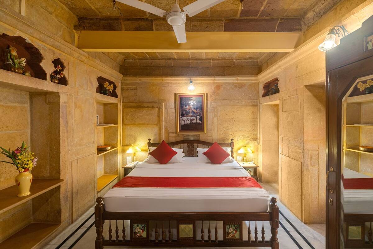 A room with a bed, shelves, a ceiling fan, and a framed picture on the wall.