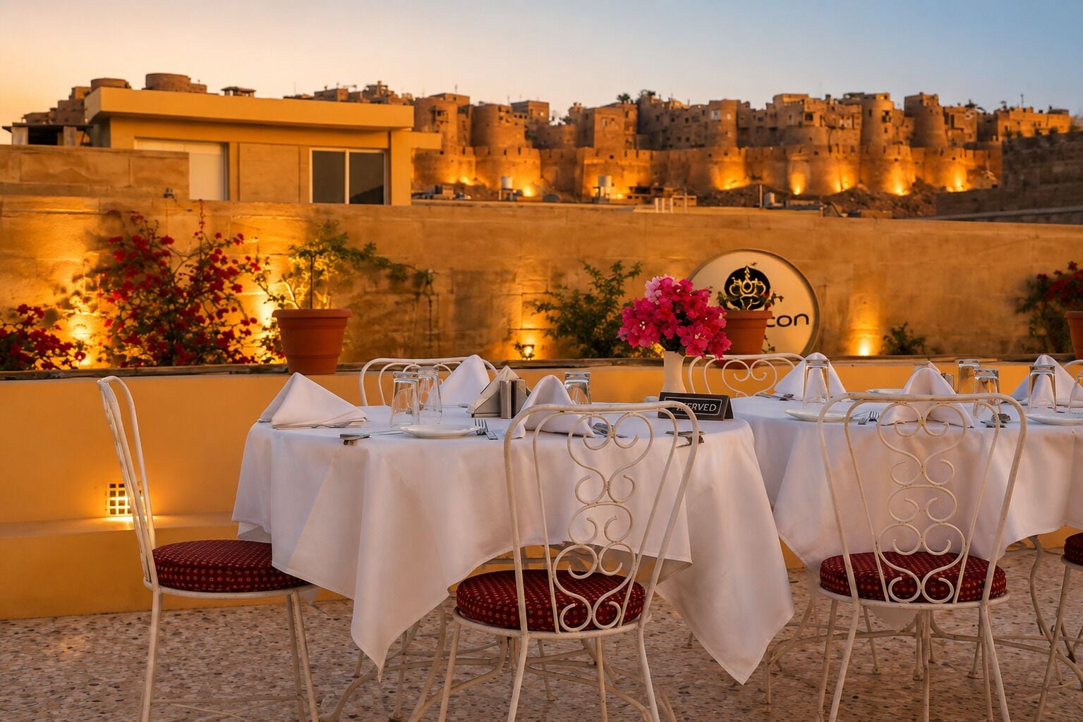 A table set for dining with a view of a historic city wall at sunset.