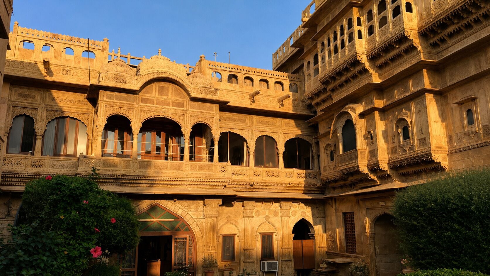 A historic building with multiple arches and balconies, featuring intricate stonework and a courtyard.