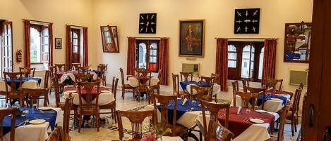 A dining area with multiple tables, chairs, and ceiling fans.