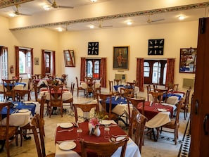A dining area with multiple tables, chairs, and ceiling fans.