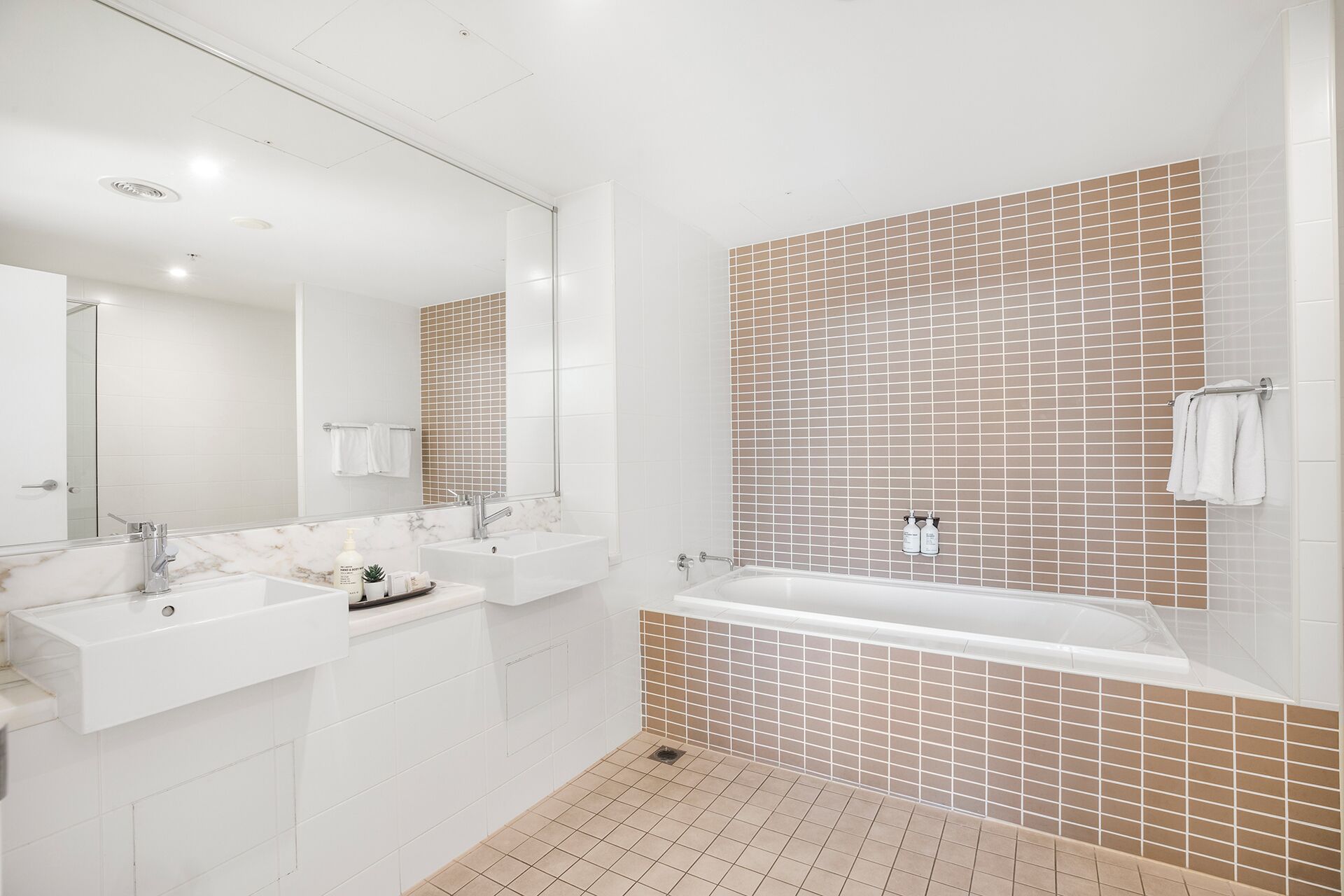 Un baño moderno con dos lavamanos, un espejo grande y una bañera.