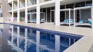 Zona de piscina con sillones de descanso y una piscina azul cristalina.