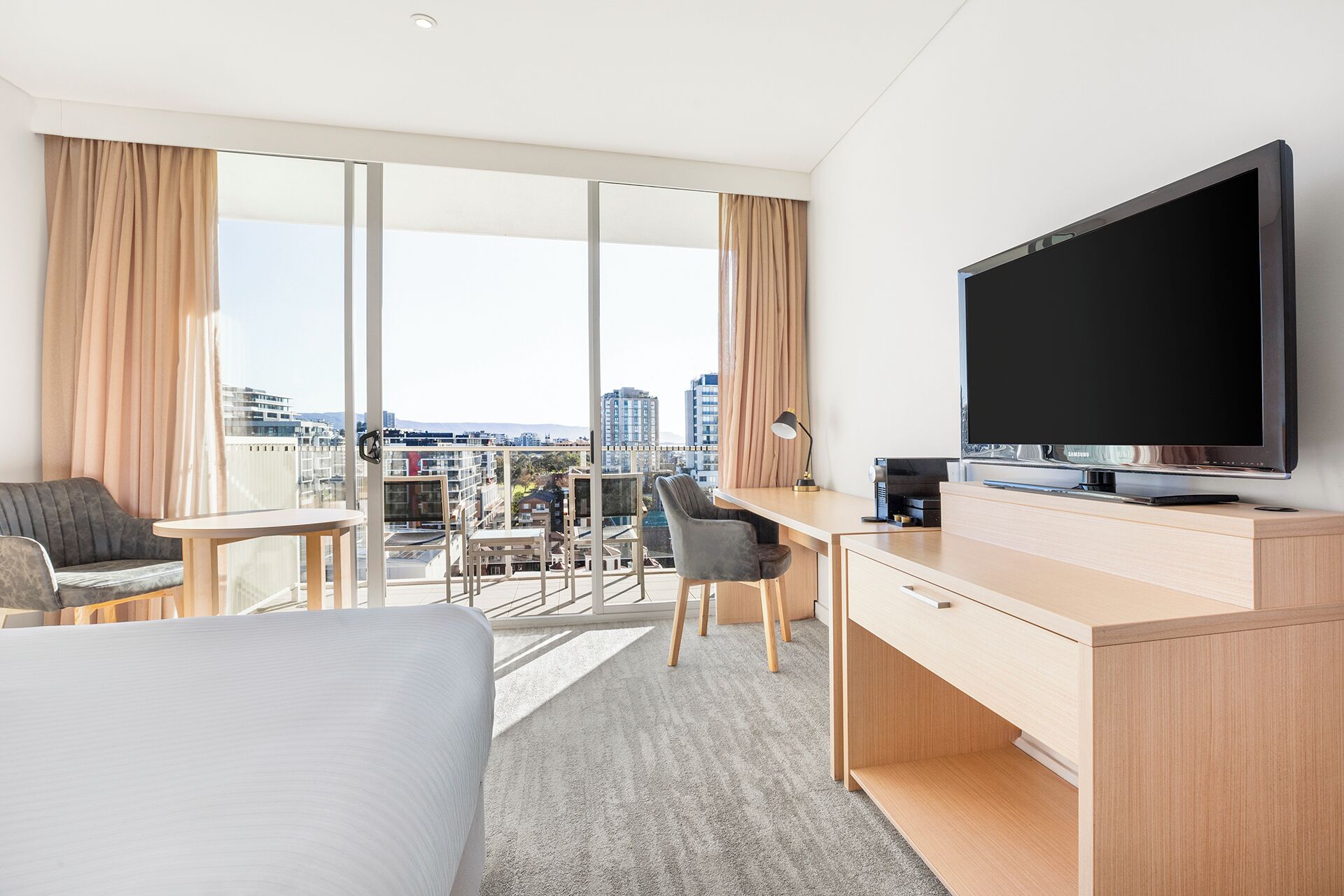 Une chambre d’hôtel équipée d’un lit, d’un bureau, d’une chaise, d’une télévision et offrant une vue sur la ville.