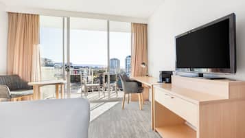 Une chambre d’hôtel équipée d’un lit, d’un bureau, d’une chaise, d’une télévision et offrant une vue sur la ville.
