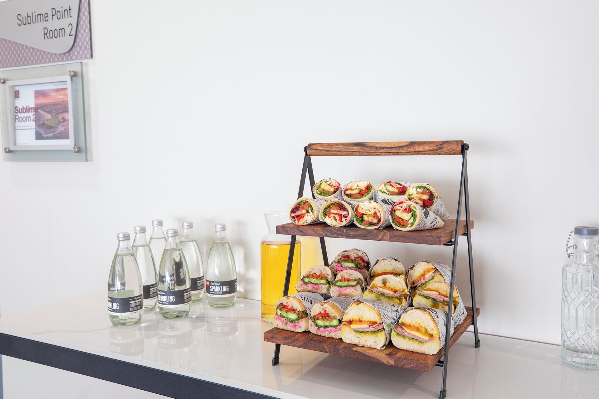 Una presentación de bocadillos con sándwiches y botellas de agua con gas.