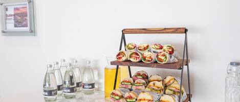 Una presentación de bocadillos con sándwiches y botellas de agua con gas.