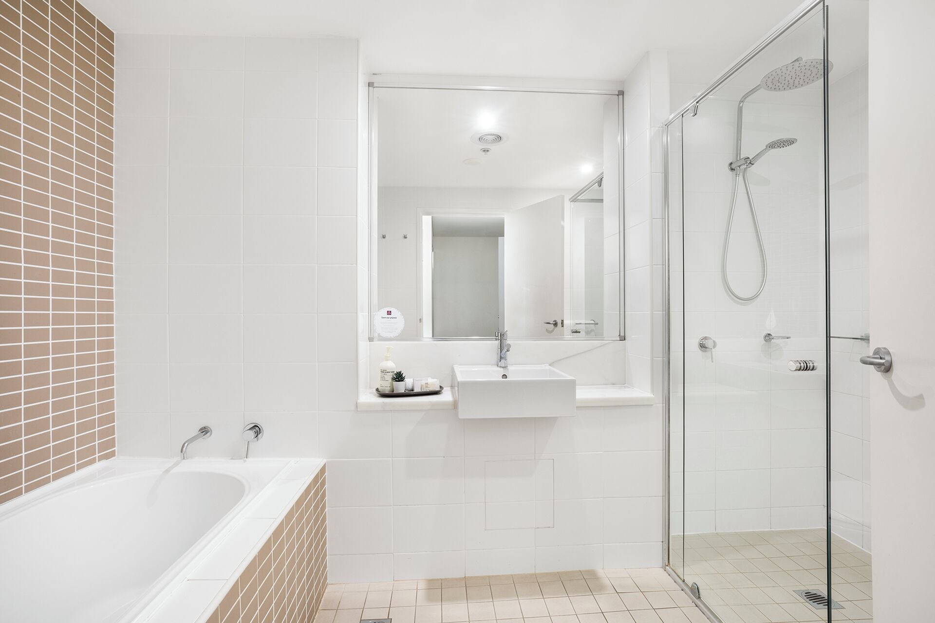 Un baño moderno con bañera, ducha con mampara de vidrio y tocador con espejo.