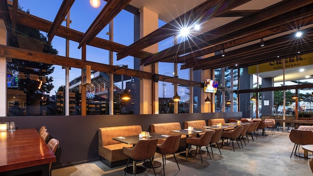 Un restaurante con vigas de madera, ventanas amplias y una combinación de cabinas y mesas.