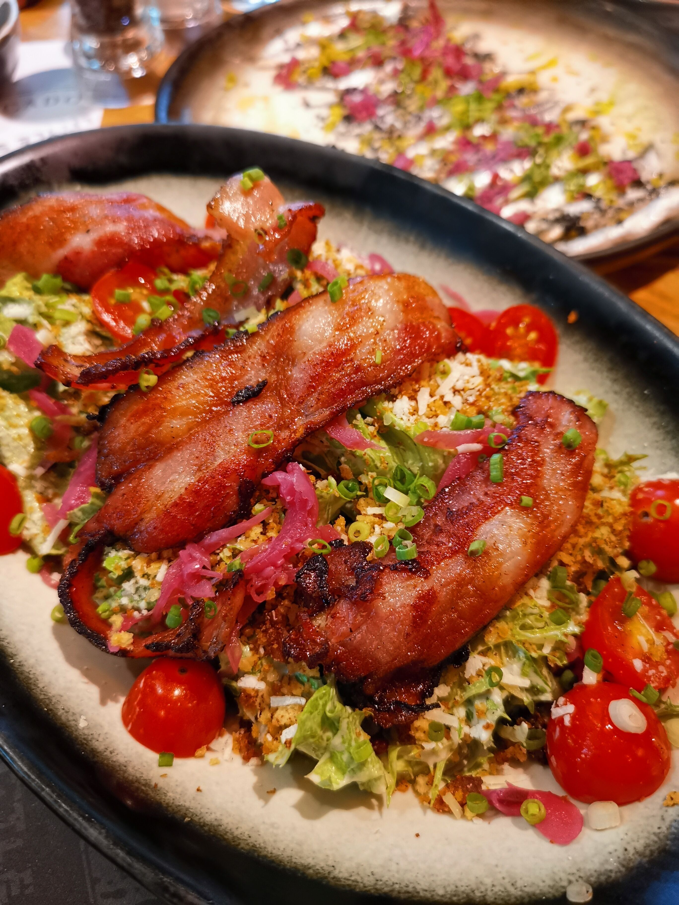 Un plato de comida con tocino, lechuga y tomates cherry.