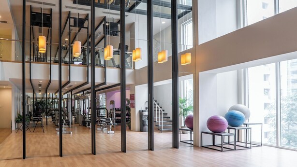 Une salle de sport spacieuse, équipée de matériel d’exercice, dotée de grandes fenêtres et d’un éclairage moderne.