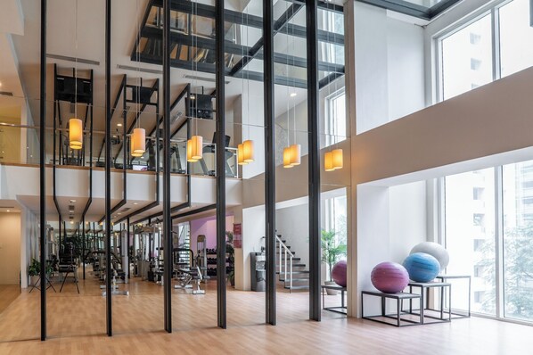 A spacious gym with exercise equipment, large windows, and modern lighting. - The Picasso Boutique Serviced Residences (Makati)
