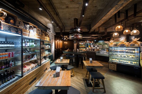 A restaurant interior with wooden tables, a bar area, and a display case with baked goods. - The Picasso Boutique Serviced Residences (Makati)