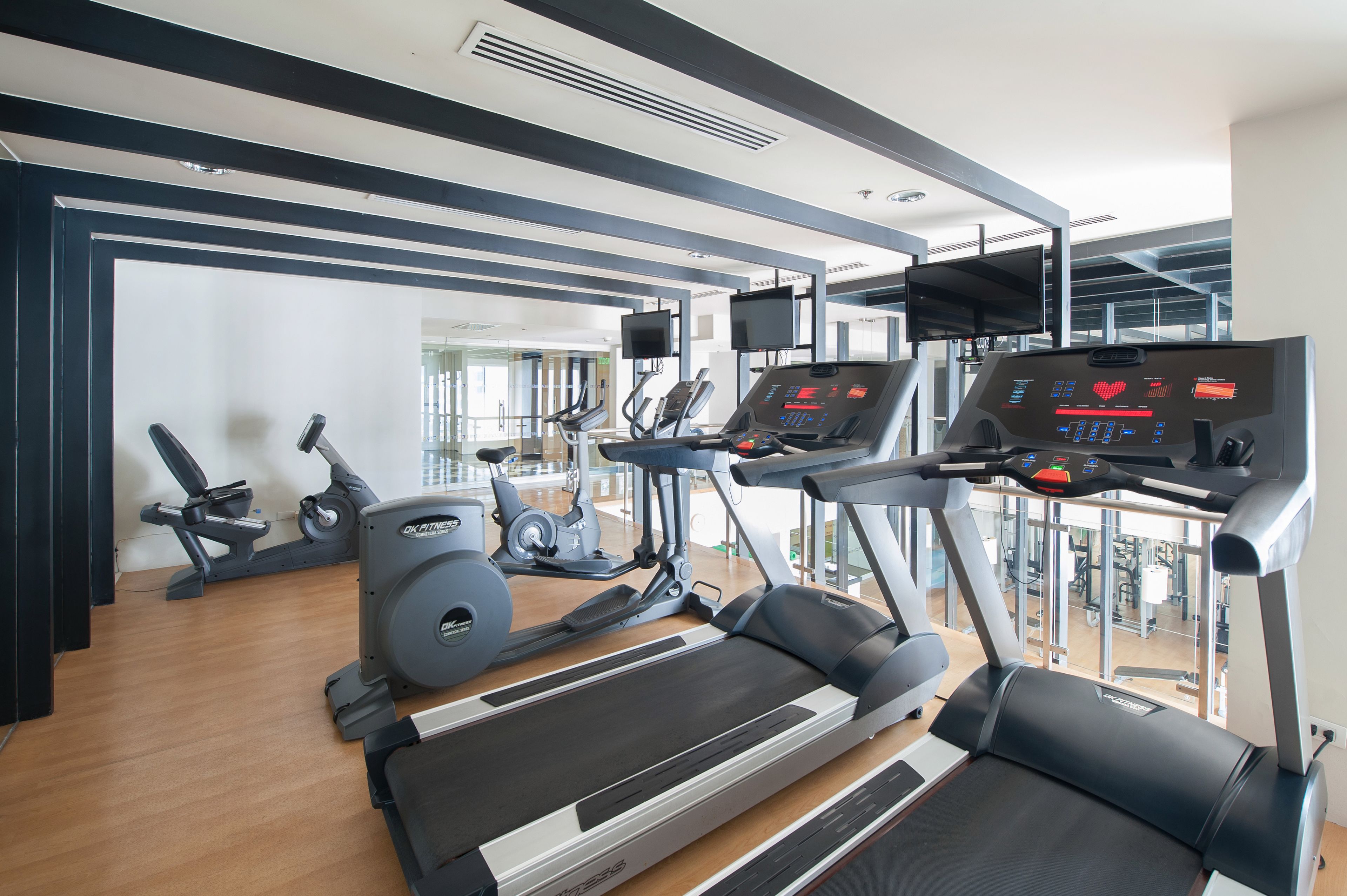 Un gimnasio con cintas de correr, elípticas y una bicicleta estática.