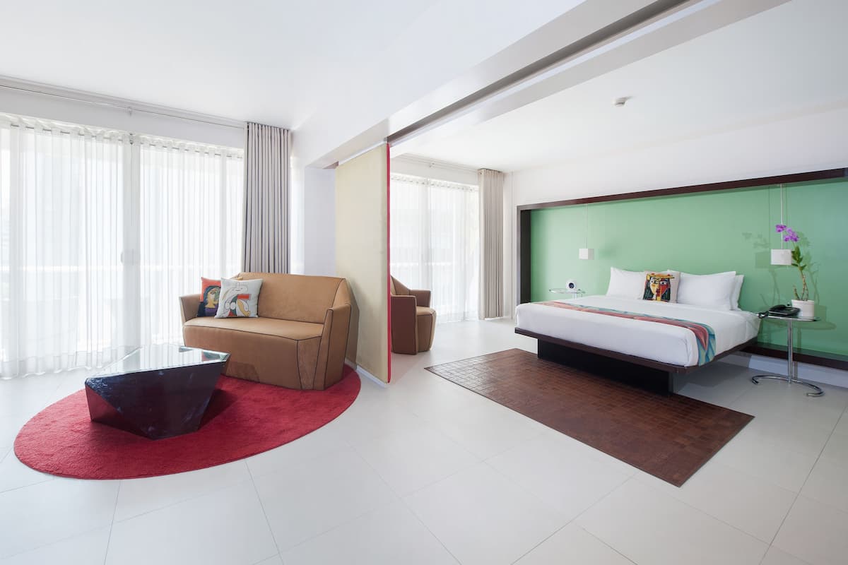 Une chambre d’hôtel moderne équipée d’un lit, d’un canapé, d’une table basse et d’un bureau.