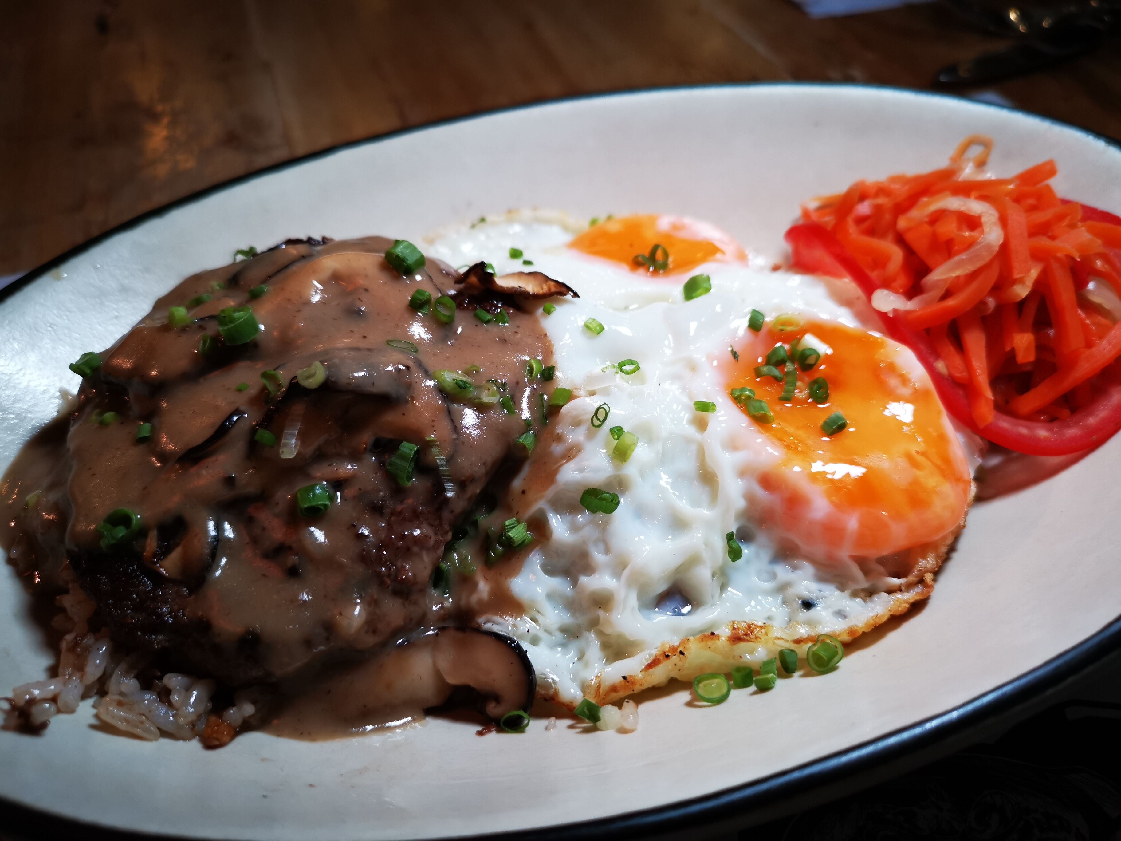 A plate of food with a steak topped with mushroom gravy, a fried egg, and a side of carrot slaw.