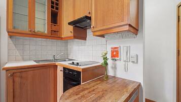 Una cocina compacta con armarios de madera, horno integrado y un lavamanos.