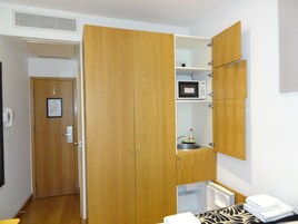 Ein kleiner Raum mit einem Holzschrank, einer Mikrowelle, einem kleinen Spülbecken und einem kompakten Kühlschrank.