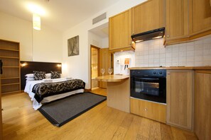 A compact hotel room with a kitchenette, a bed with patterned bedding, and a small dining area. - Studios2Let Bloomsbury (London)