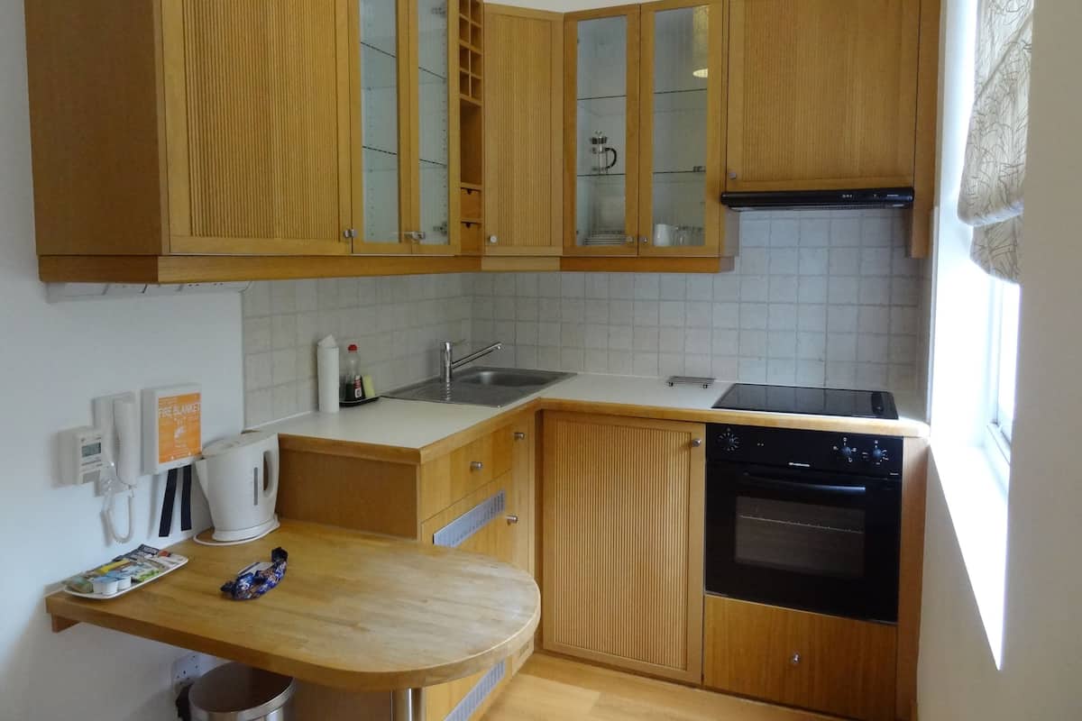 A compact kitchen with wooden cabinets, a dishwasher, a stove, and a sink.