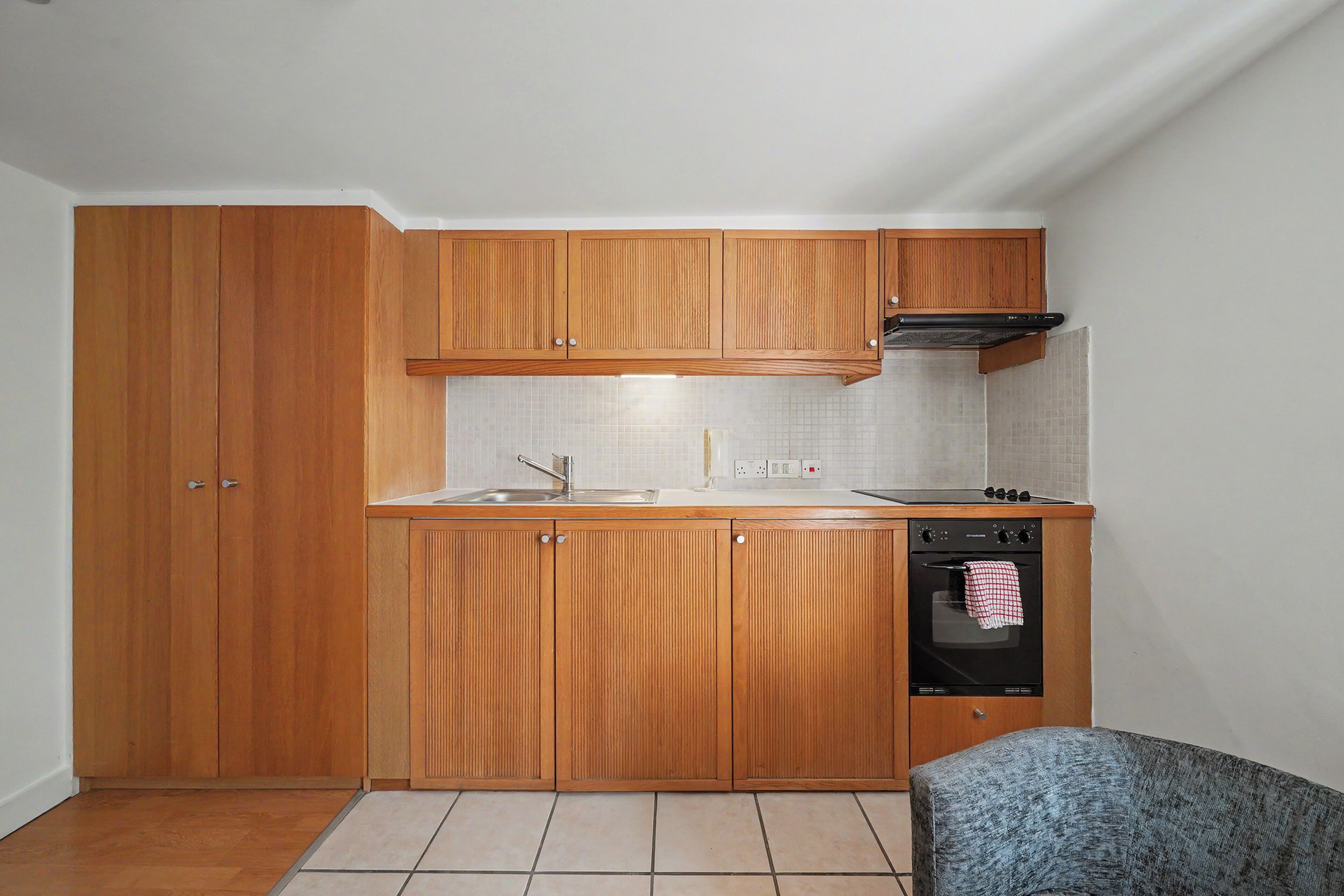 Cocina compacta con armarios de madera, un lavamanos, estufa y horno.