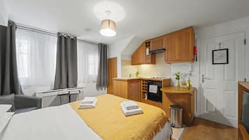 A compact hotel room with a bed, a small kitchenette, and a bathroom.
