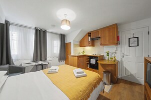 Habitación de hotel compacta con cama, kitchenette pequeña y baño.
