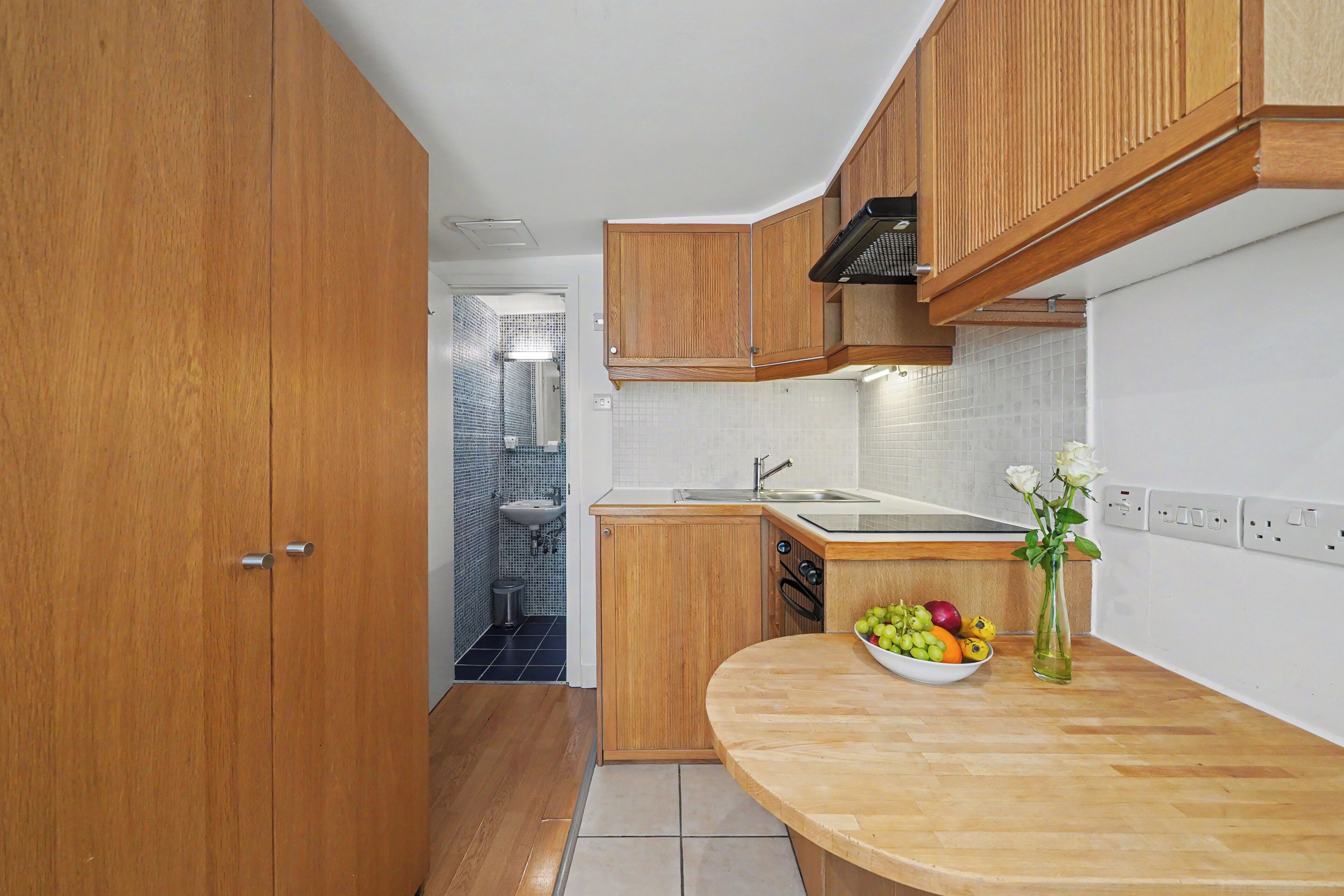 A kitchen with wooden cabinets, a sink, and a fruit bowl on the counter.