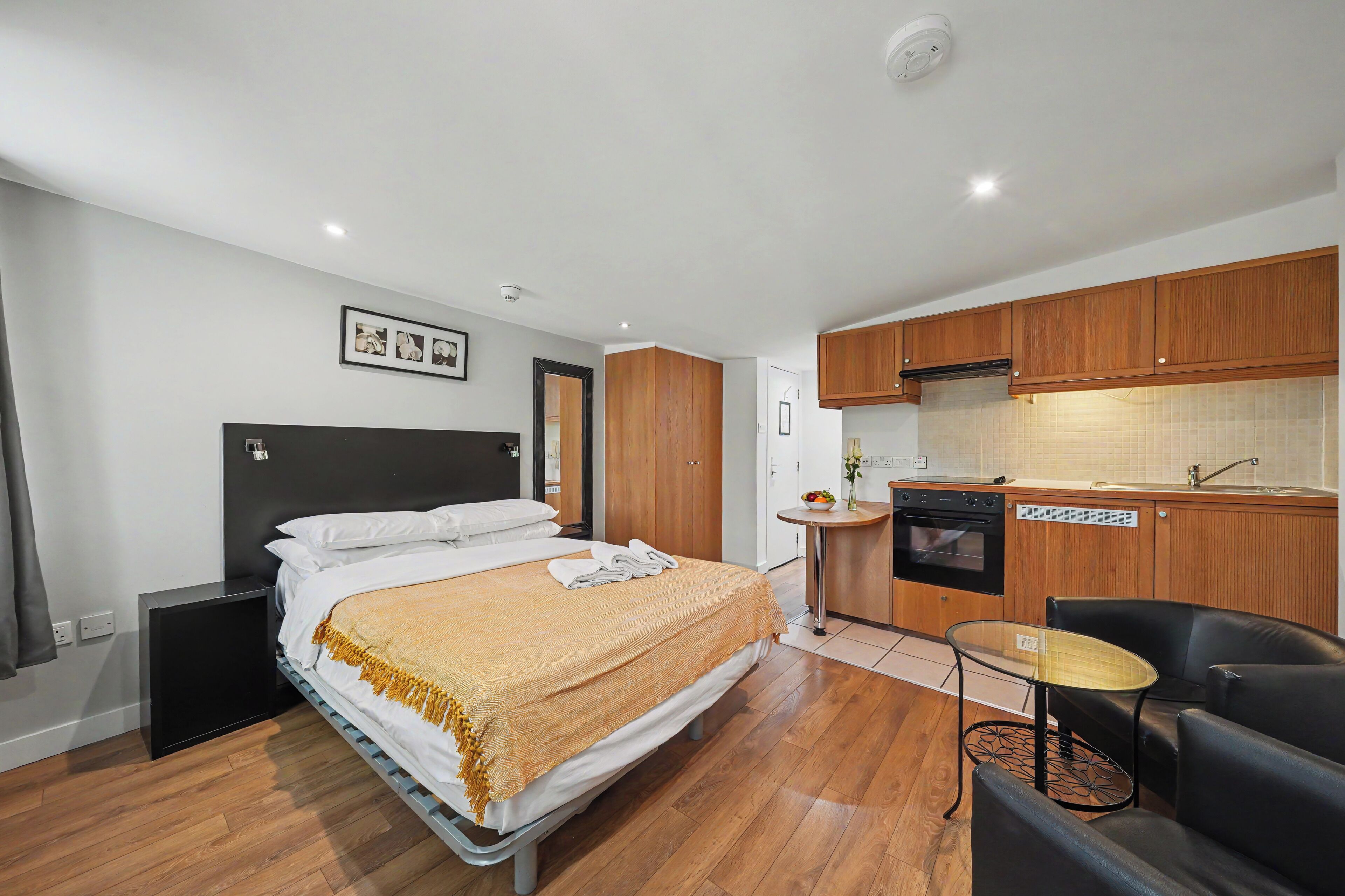 Una habitación de hotel con cama, kitchenette pequeño, zona de estar y baño.