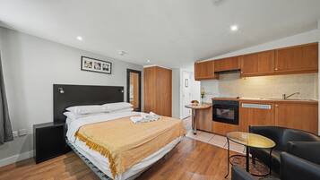 Una habitación de hotel con cama, kitchenette pequeño, zona de estar y baño.