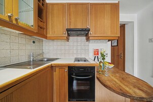 A kitchen with wooden cabinets, a stainless steel sink, a built-in oven, and a white countertop.