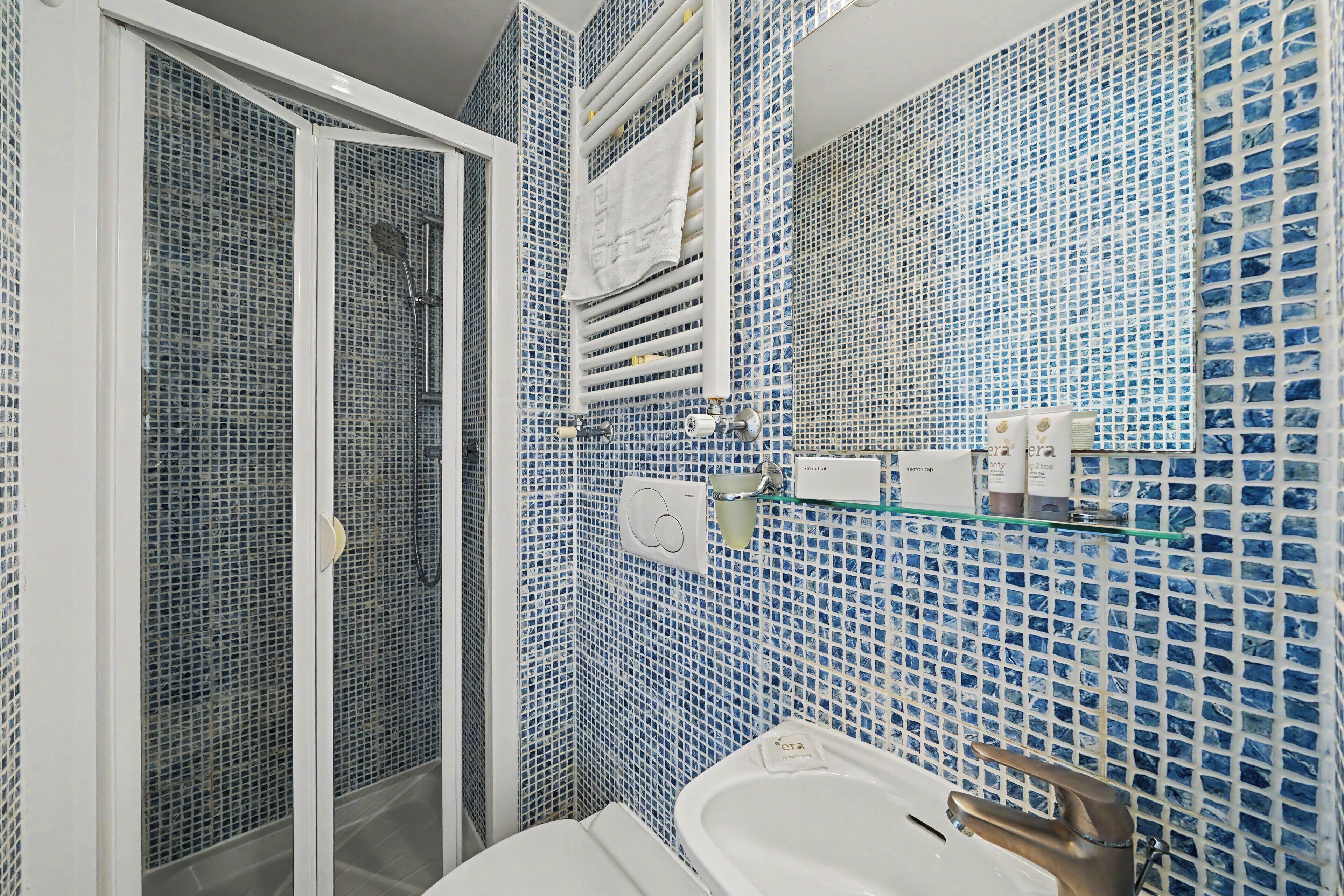 Un baño con ducha, lavamanos y espejo.