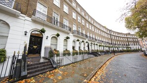 A row of white brick townhouses with black railings and a curved driveway.