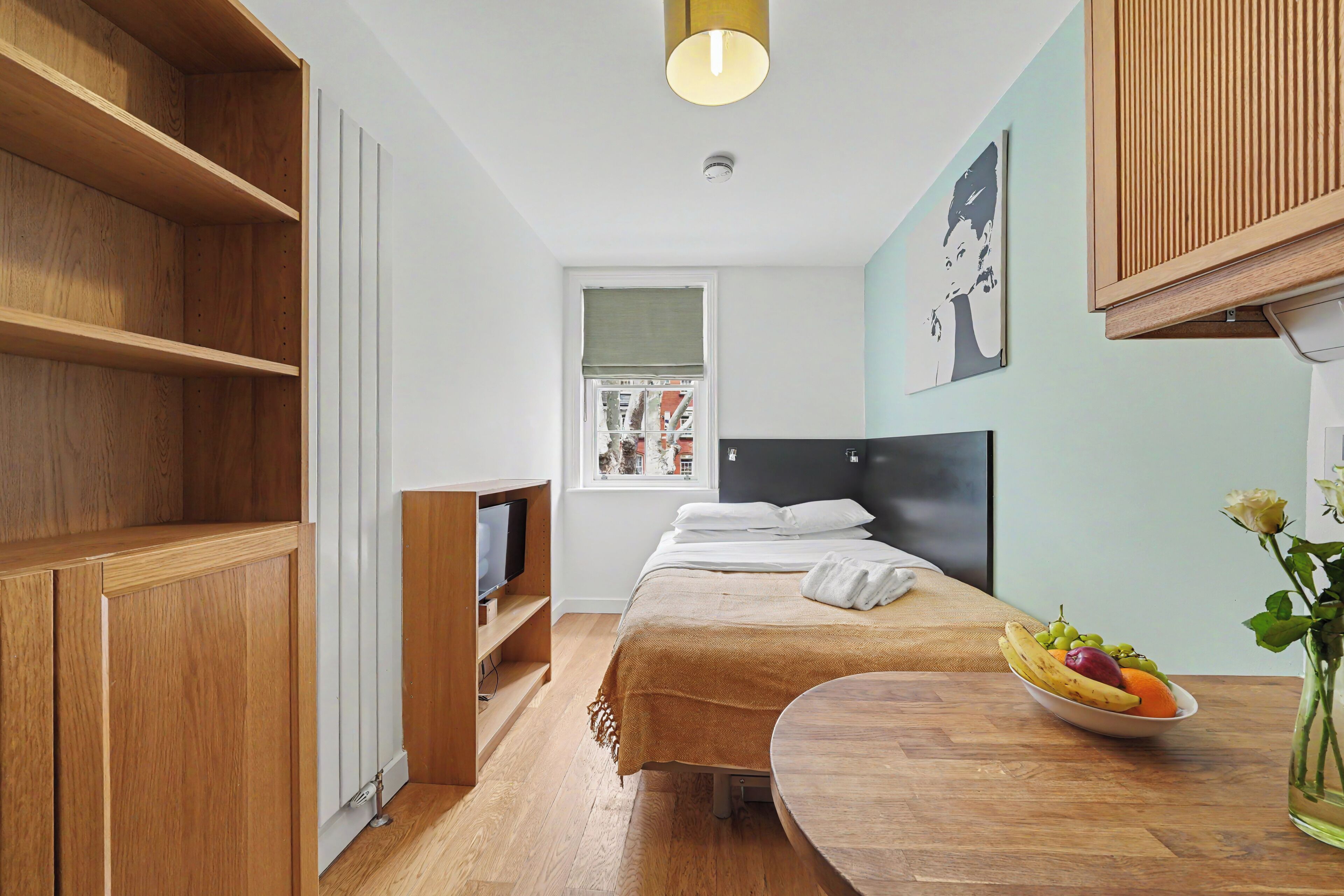 Een moderne slaapkamer met een bed, nachtkastje en uitzicht op de straat.