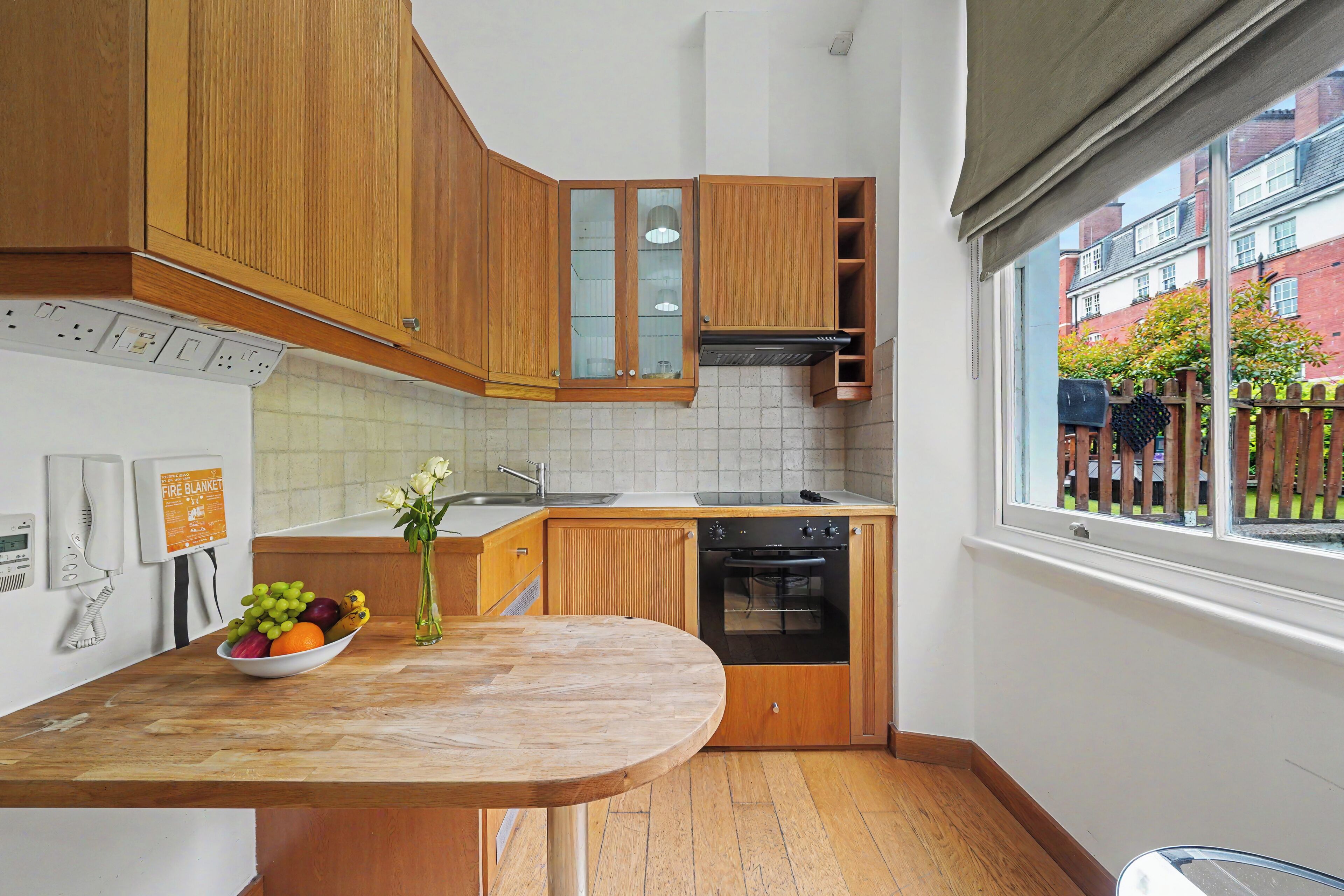 A kitchen with wooden cabinets, a built-in oven, a sink, and a window with a view of the outside.