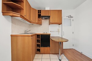 Uma cozinha compacta com armários de madeira, máquina de lavar louça embutida e uma bancada pequena.