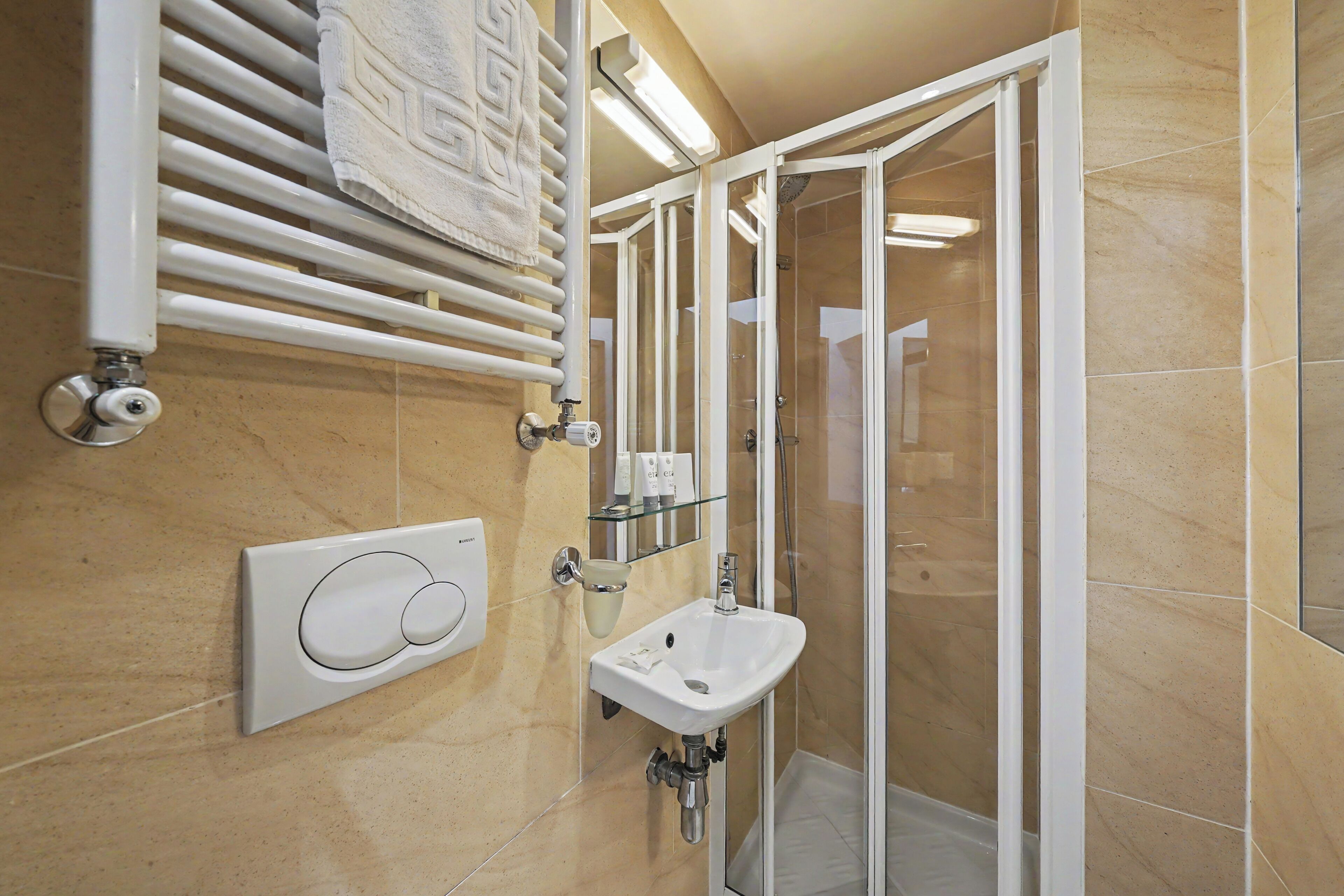 A modern bathroom with a glass shower enclosure, a wall-mounted towel warmer, and a sink with a glass soap dispenser.