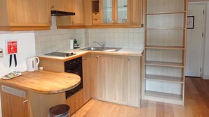 A compact kitchen with wooden cabinets, a built-in dishwasher, a sink, and a small countertop.