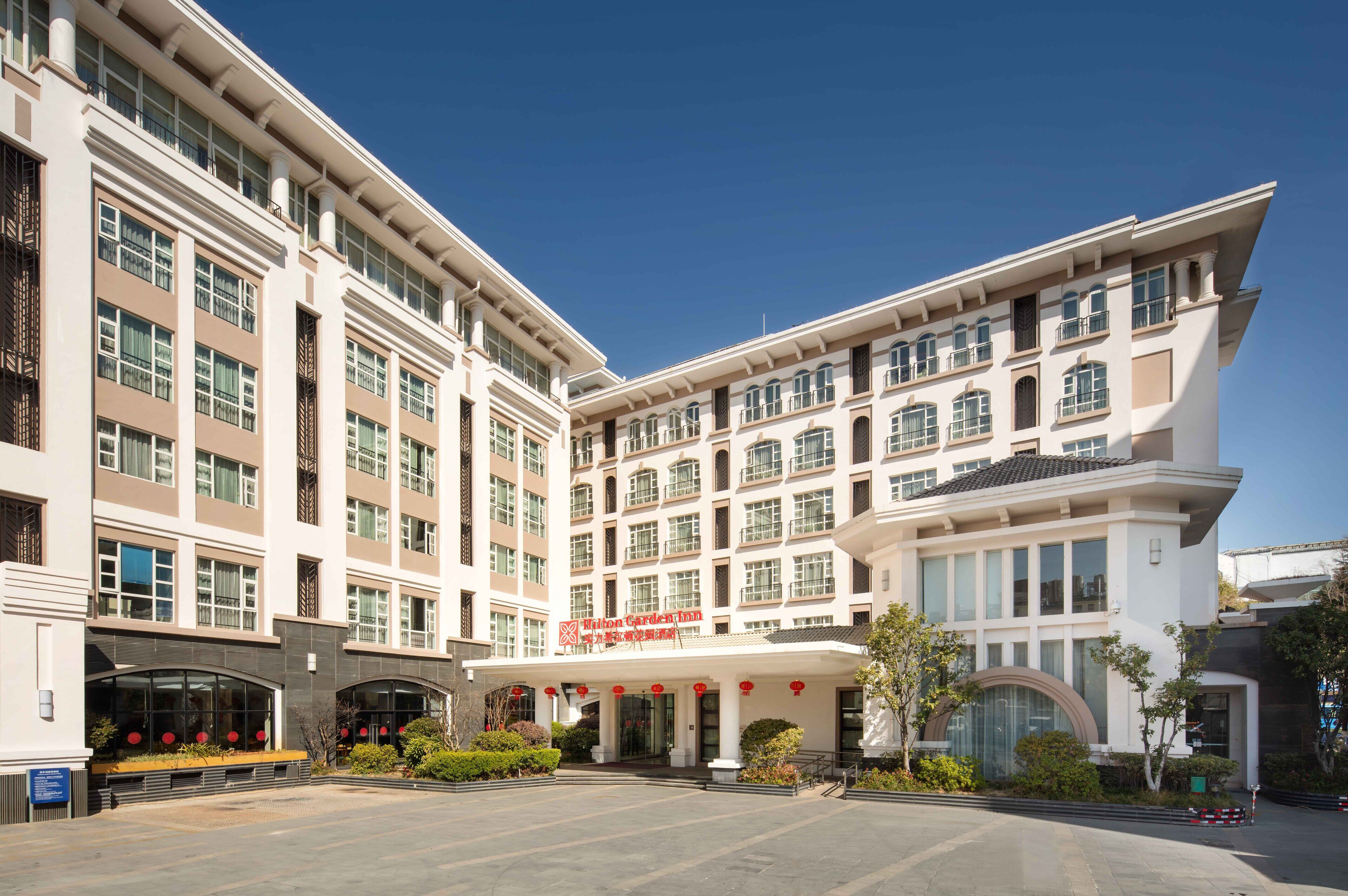 A multi-story hotel with a prominent entrance, large windows, and a clear sky.