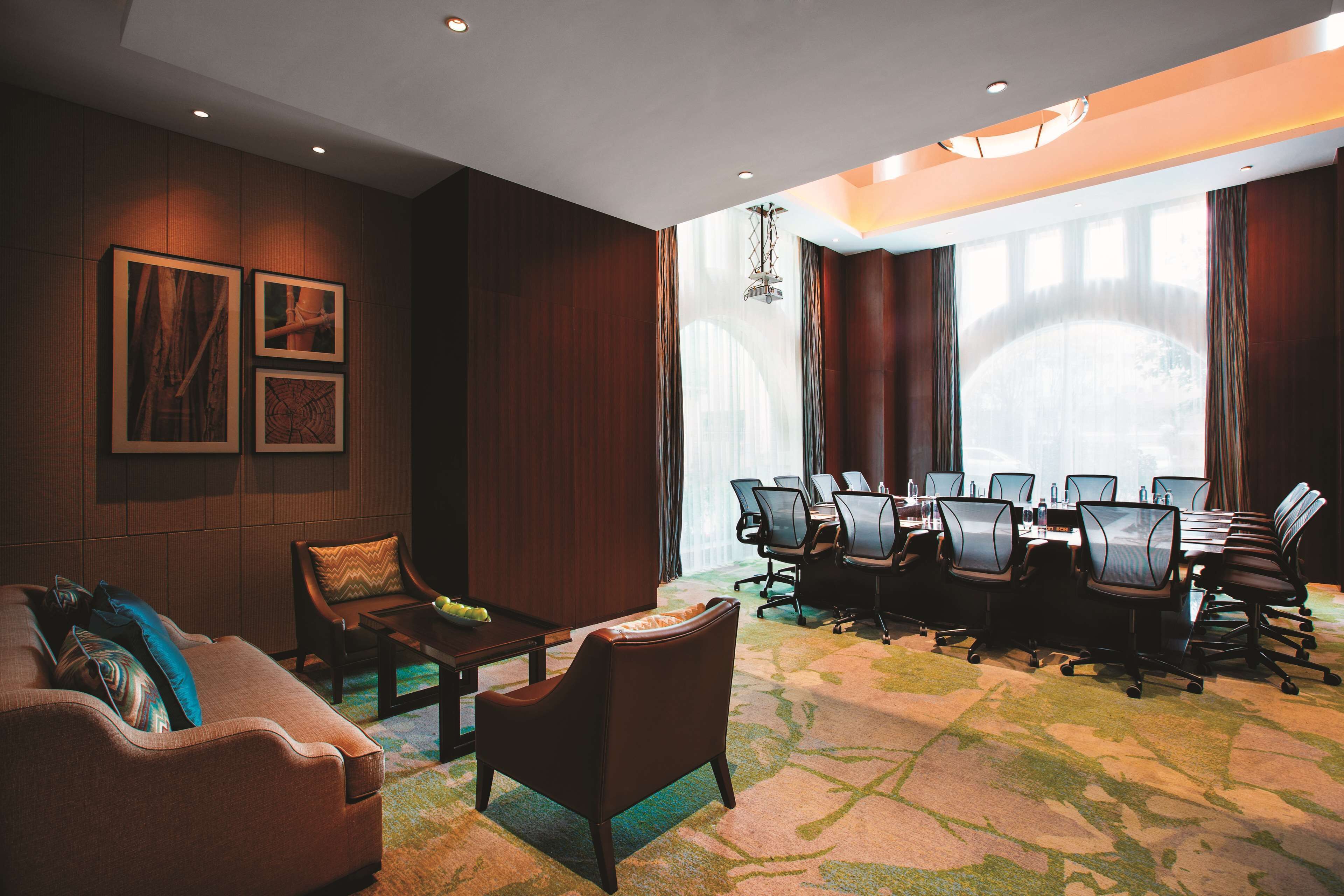 A conference room with a long table, multiple chairs, a sofa, and a coffee table.