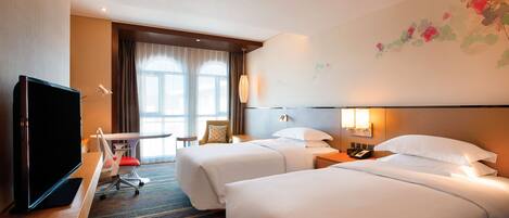 Een hotelkamer met twee bedden, een bureau met een televisie, een stoel en een raam met gordijnen.
